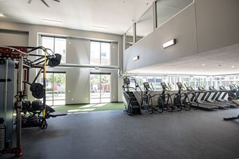 A gym with a row of exercise bikes and a weight training area.
